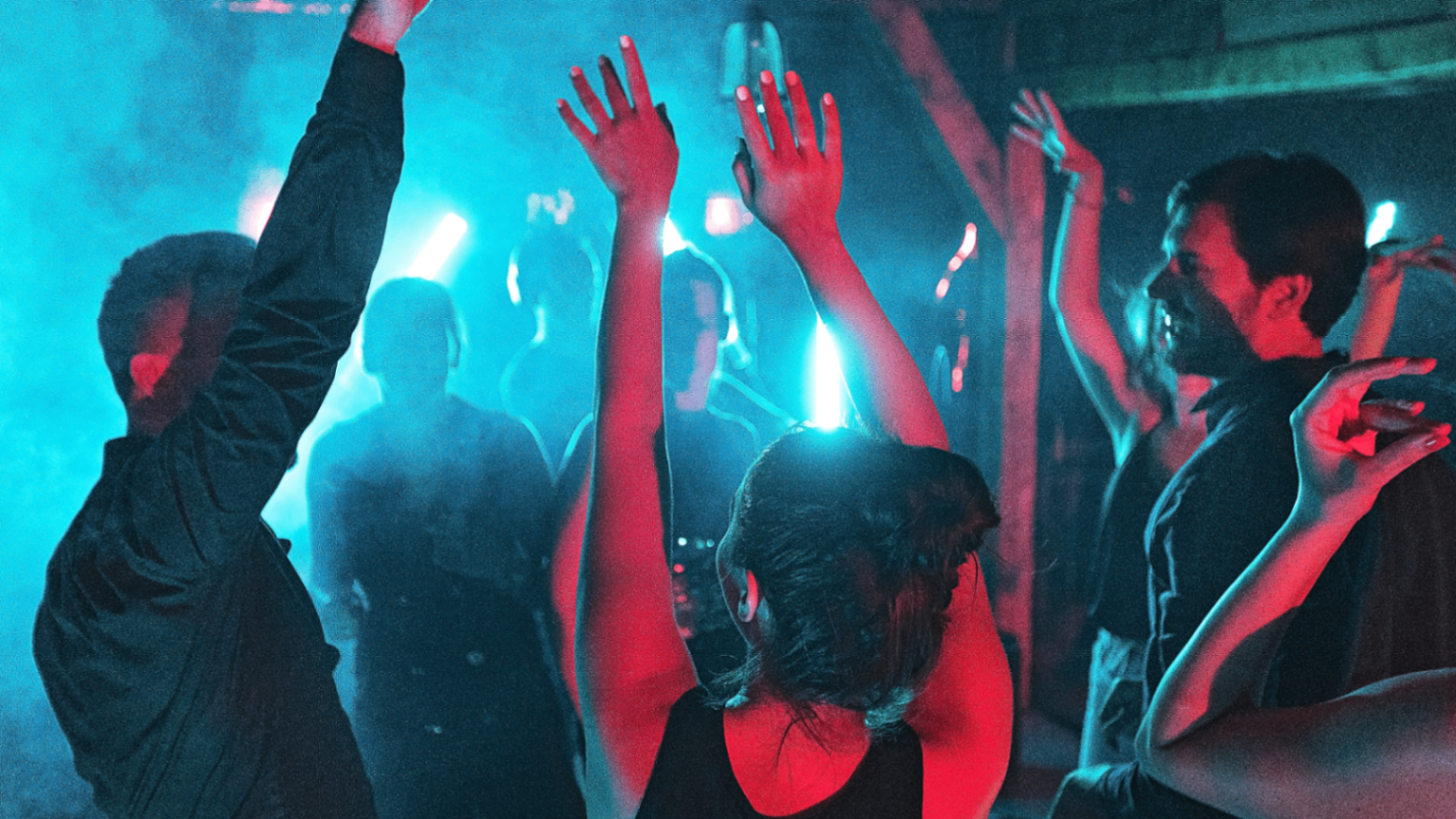 Dance floor gathered around a live DJ set with blue and red lighting