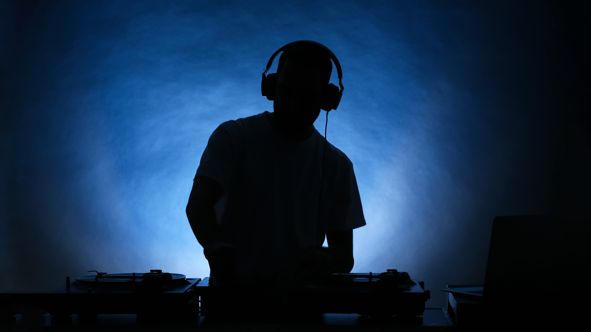 Silhouetted DJ performing against blue stage lighting