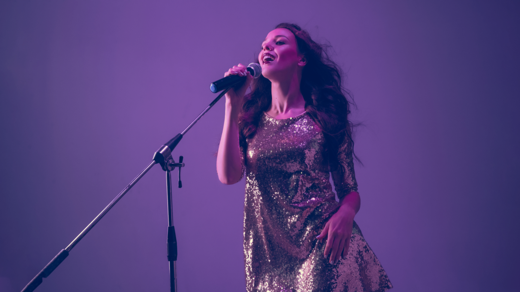 Singer performing live on stage under purple lights